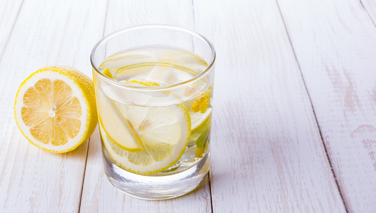 A refreshing glass of water with lemon and fruit on a table