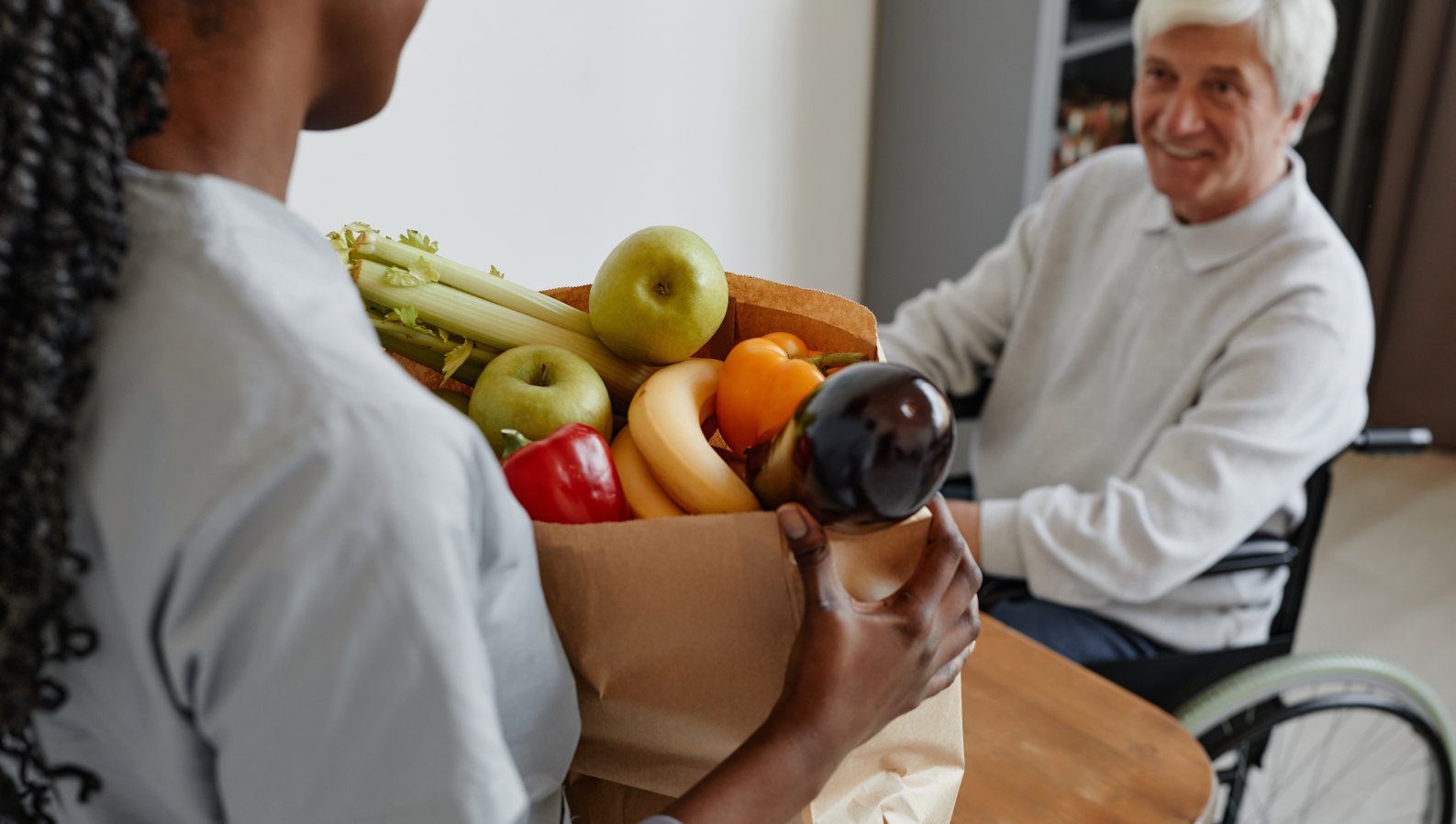 A caregiver bringing groceries to help a senior at home